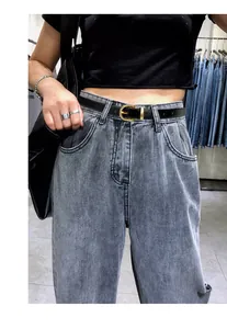 Klassischer schwarzer Ledergürtel mit goldener Hufeisenschnalle auf grauen Jeans
