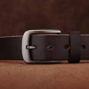 Gros plan sur une ceinture en cuir marron foncé avec boucle ardillon en métal brossé