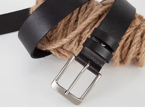 Detail of black leather men's belt with matte silver buckle and rustic rope background