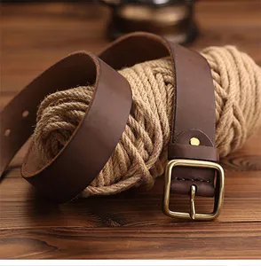 Gros plan d'une ceinture en cuir marron vintage avec boucle en laiton sur corde