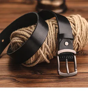 Close-up of black leather belt with matte metal pin buckle on rustic rope and wood