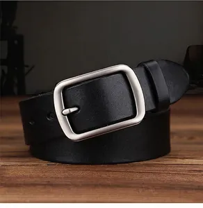 Close-up of black genuine leather belt with brushed metal pin buckle on wooden surface