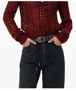 Détail d'une ceinture en cuir véritable marron foncé avec boucle argentée mate sur un jean