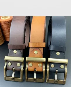 Detalle de hebillas de latón vintage en cinturones de cuero negro, marrón y tostado