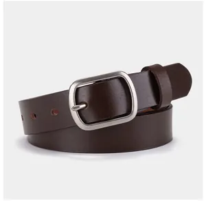 Détail de la texture d'une ceinture en cuir marron foncé avec boucle ardillon argentée