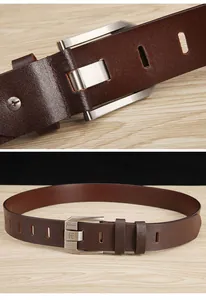 Detail of dark brown leather belt with brushed silver metal buckle and engraved logo
