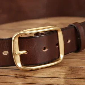 Men's dark brown leather belt with vintage brass pin buckle on dark wood table