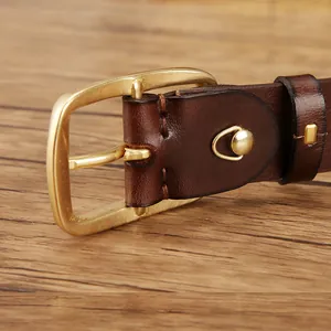 Men's retro dark brown leather belt with matte brass pin buckle on a wooden surface
