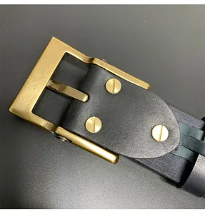 Detalle de hebilla de latón vintage con triple tornillo en cinturón de cuero negro