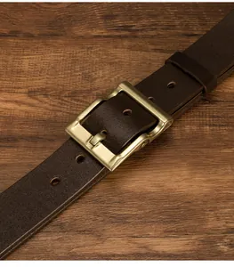 Dettaglio di cintura in pelle marrone scuro con fibbia ad ardiglione in ottone vintage
