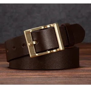 Dettaglio della cintura in pelle marrone scuro con fibbia in ottone su base di legno