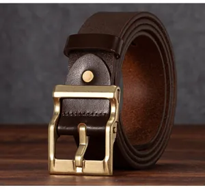 Dettaglio cintura in pelle marrone con fibbia in ottone su fondo in legno scuro