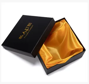 Detail van vierkante zwarte geschenkdoos met gouden bedrukking en gele satijnen voering