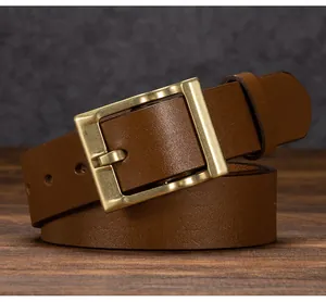 Dettaglio macro della cintura in vera pelle marrone con fibbia vintage in ottone su legno