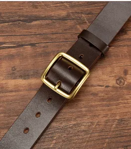 Close-up of vintage brown leather belt with rustic brass buckle on wooden texture