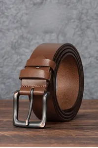 Détail d'une ceinture en cuir de vachette marron avec boucle en métal mat rétro