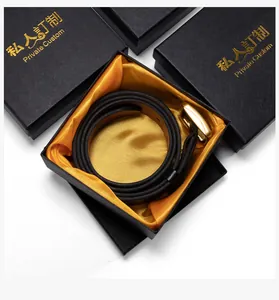 Detail van een zwarte leren riem met gouden gesp in een luxe Saffiano geschenkdoos