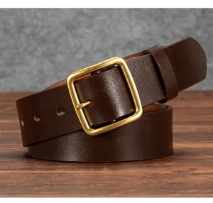 Close-up of vintage dark brown leather belt with brass square buckle on wood surface