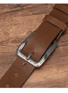 Close-up of brown leather belt featuring an antique silver floral engraved alloy buckle