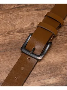Détail d'une ceinture en cuir marron vintage avec boucle en métal gris foncé sur bois