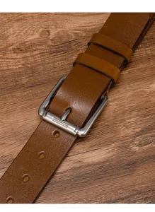 Detail view of brown leather belt with brushed silver pin buckle on dark wood background