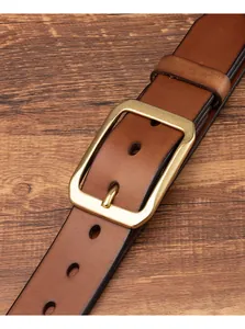 Dettaglio della cintura in pelle marrone vintage con fibbia in ottone su legno scuro