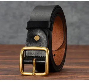 Detail of vintage black leather belt with brass square buckle on a wooden table