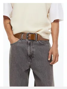 Gros plan d'une ceinture en cuir marron vintage avec boucle ardillon sur un jean