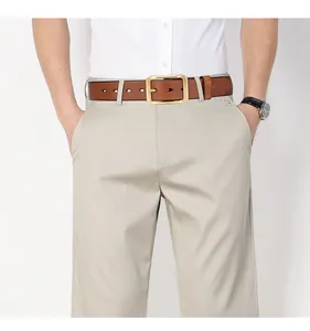 Dettaglio cintura in vera pelle marrone con fibbia in ottone su pantaloni in cotone beige