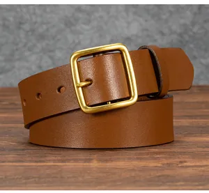Detail view of vintage brown genuine leather belt with classic brass pin buckle on wood