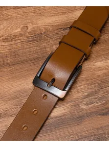 Dettaglio macro della cintura in pelle marrone con fibbia ad ardiglione in bronzo