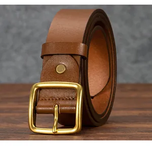 Detail of genuine brown leather belt with rustic brass buckle on wooden texture background