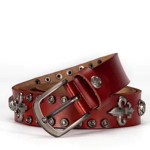 Dettaglio di cintura in pelle rossa scura con borchie punk e distintivi in metallo a giglio