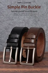 Macro shot of two genuine leather belts with brushed metal buckles on a wood table