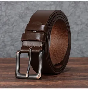 Détail d'une ceinture en cuir marron vintage avec boucle en métal sur bois sombre