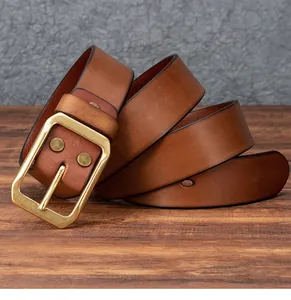 Dettaglio cintura vintage in pelle marrone con fibbia dorata su piano in legno