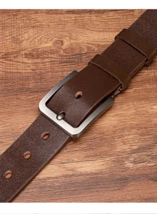 Detailed view of brown leather belt with matte silver pin buckle on wood background
