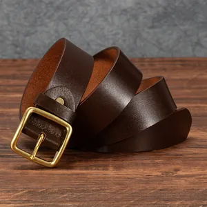 Vintage dark brown leather belt for men with retro brass pin buckle on a wooden surface