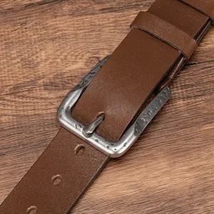 Vintage men's dark brown leather belt with embossed antique silver buckle on wood