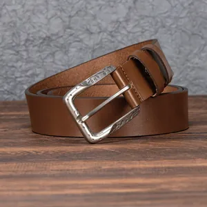 Vintage men's brown leather belt with retro carved alloy buckle on a wooden background