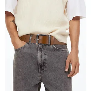 Ceinture vintage en cuir marron pour homme avec boucle en métal sur jean gris