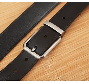 Detail of classic black leather belt with a brushed silver metal buckle on a bamboo mat