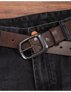 Close-up of vintage brown cowhide leather belt with gun-grey buckle on black jeans