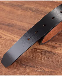 Macro detail of black vintage leather belt strap showing five holes and tan inner layer