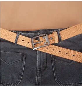 Close-up of light brown pebble grain leather belt with matte grey pin buckle on jeans