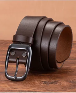Macro shot of vintage dark brown leather belt with matte metal buckle on wood surface