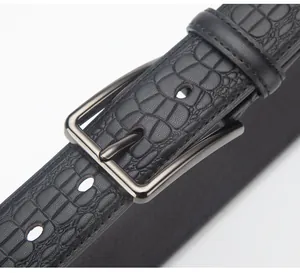 Detail shot of men's black leather belt featuring crocodile embossing and gunmetal buckle