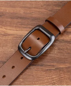 Close-up of vintage brown cowhide leather belt with antique metal buckle on wood