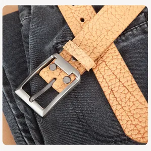 Macro detail of camel pebble grain leather belt with brushed metal pin buckle