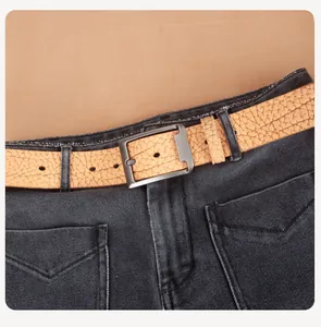 Close-up of light brown leather belt with lychee texture and metal pin buckle on jeans